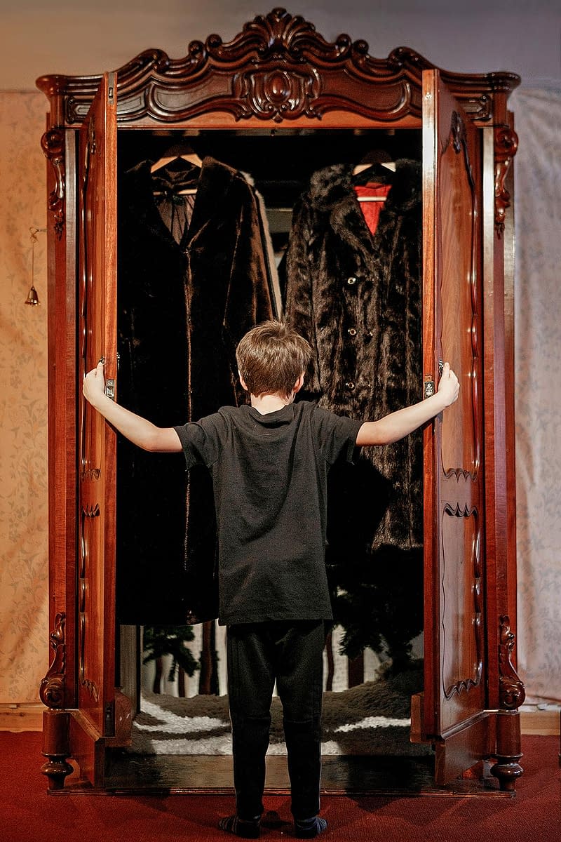 A boy opens the wardrobe door to Narnia