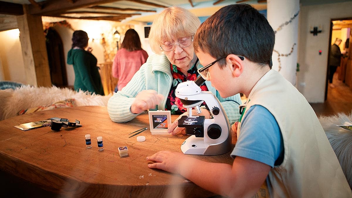 Elderly lady and young boy look at objects through a microscope